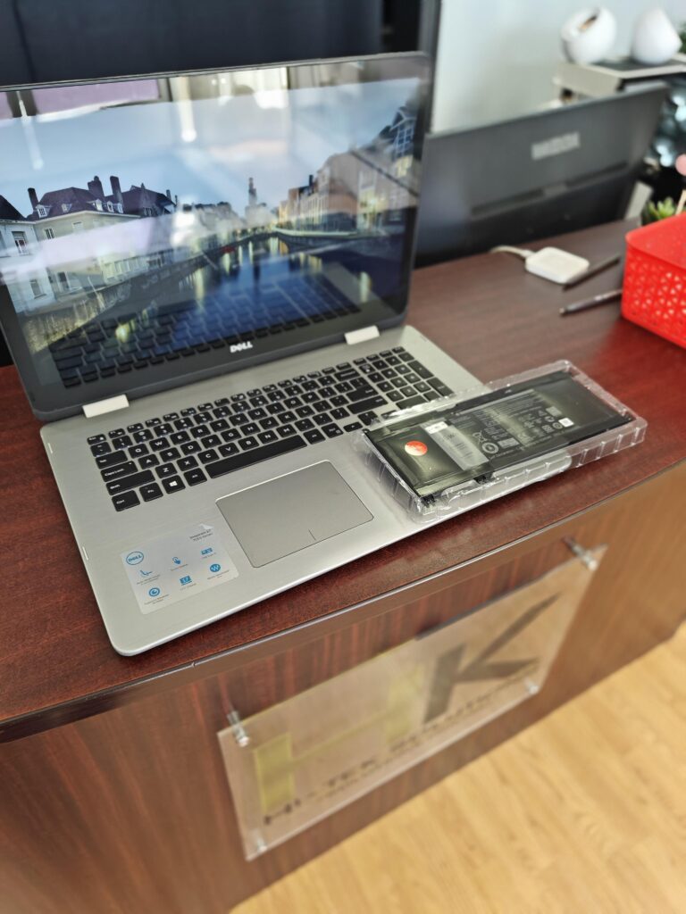 Laptop Dell con una batería de repuesto en el mostrador de Hi-Tek Solutions.